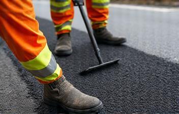 Workers applying asphalt patch to a road surface